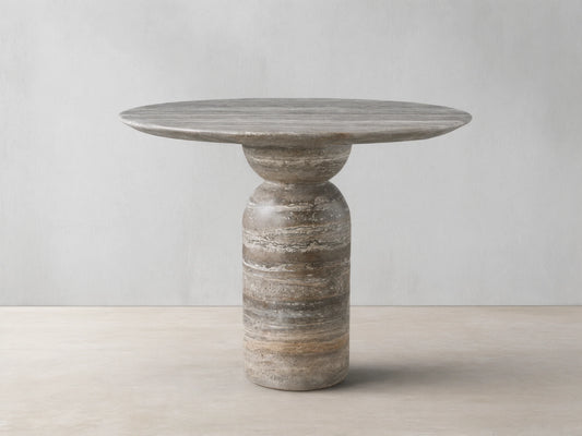 Perth Stone Bistro Table with a round top and a tapered cylindrical base, displaying natural stone patterns in earthy brown, beige, and grey.