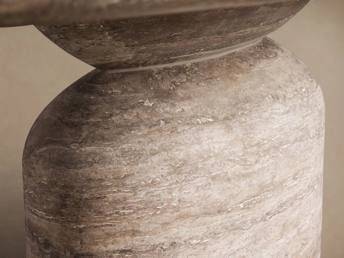 Front view of the oval Perth Oval Stone Dining Table with a natural travertine top and a round, textured pedestal base.