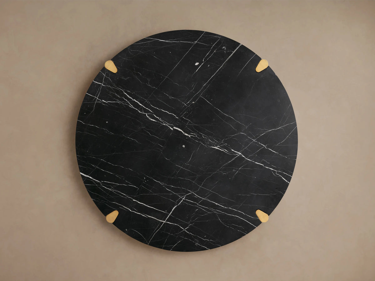 Pyet Round Dining Table featuring a black marble top with white veining, supported by solid red oak legs, close-up view.