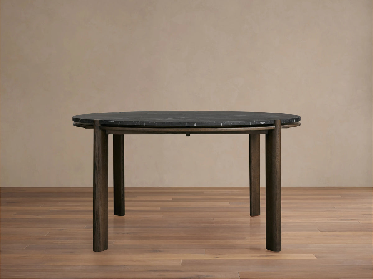 Round dining table with a dark Carrara marble top and solid red oak wood legs. The table has a minimalist design with a subtle sheen finish.