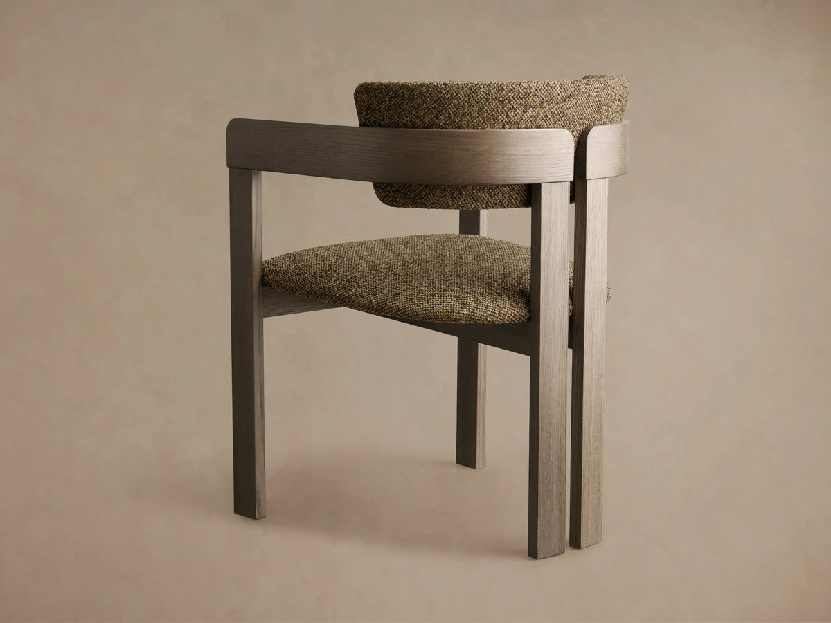 Angled front view of the Rodin Dining Arm Chair, featuring a grey ash wood frame and textured greenish-brown upholstered seat and back.