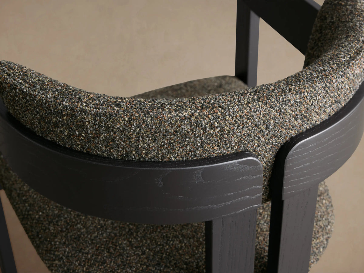 Front-side view of the black ash wood Rodin Dining Arm Chair with speckled gray and green upholstered seat and backrest.
