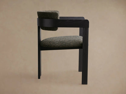 Close-up of the back and armrest of the Rodin Dining Arm Chair, featuring dark ash wood and textured gray-green upholstery.