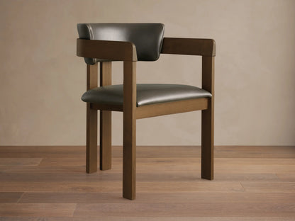 Rodin Faux Leather Arm Chair. Dark brown wooden frame with dark gray faux leather seat and back, angled on wood floor.