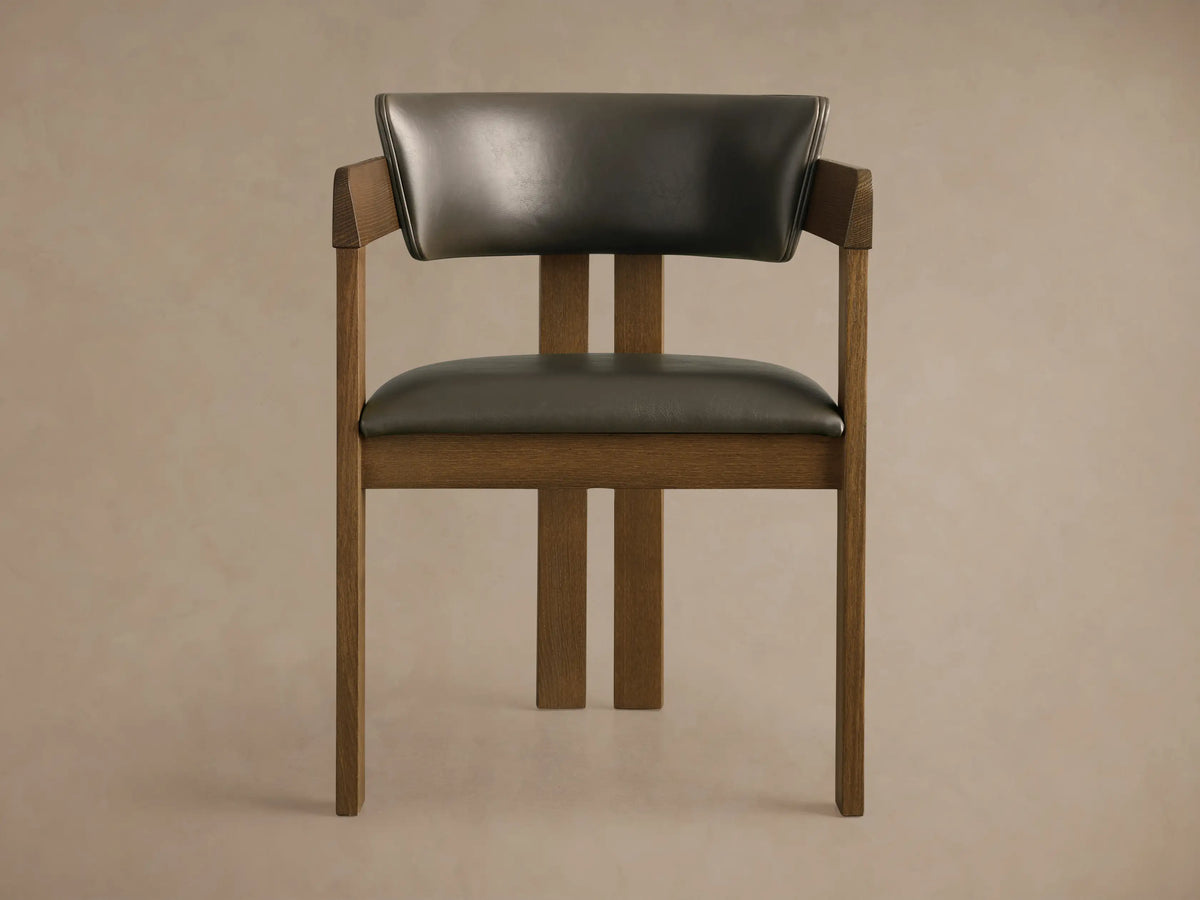 Rodin Faux Leather Arm Chair. Dark brown wooden frame with dark gray faux leather seat and back, angled on wood floor.