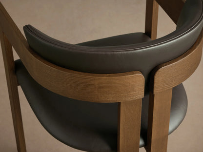 Rodin Faux Leather Arm Chair, front. Ash wood frame, dark grey faux leather seat & curved backrest, integrated armrests.