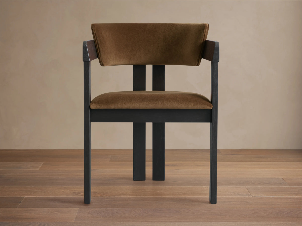 Rodin Dining Arm Chair made of ash wood with a dark frame and light brown cushioned seat and backrest, on a wooden floor.