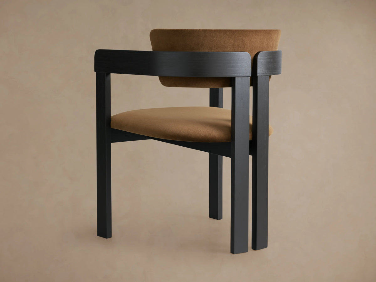 Rodin Dining Arm Chair in close-up, showing its curved ash wood frame with a dark finish and a soft tan fabric backrest.