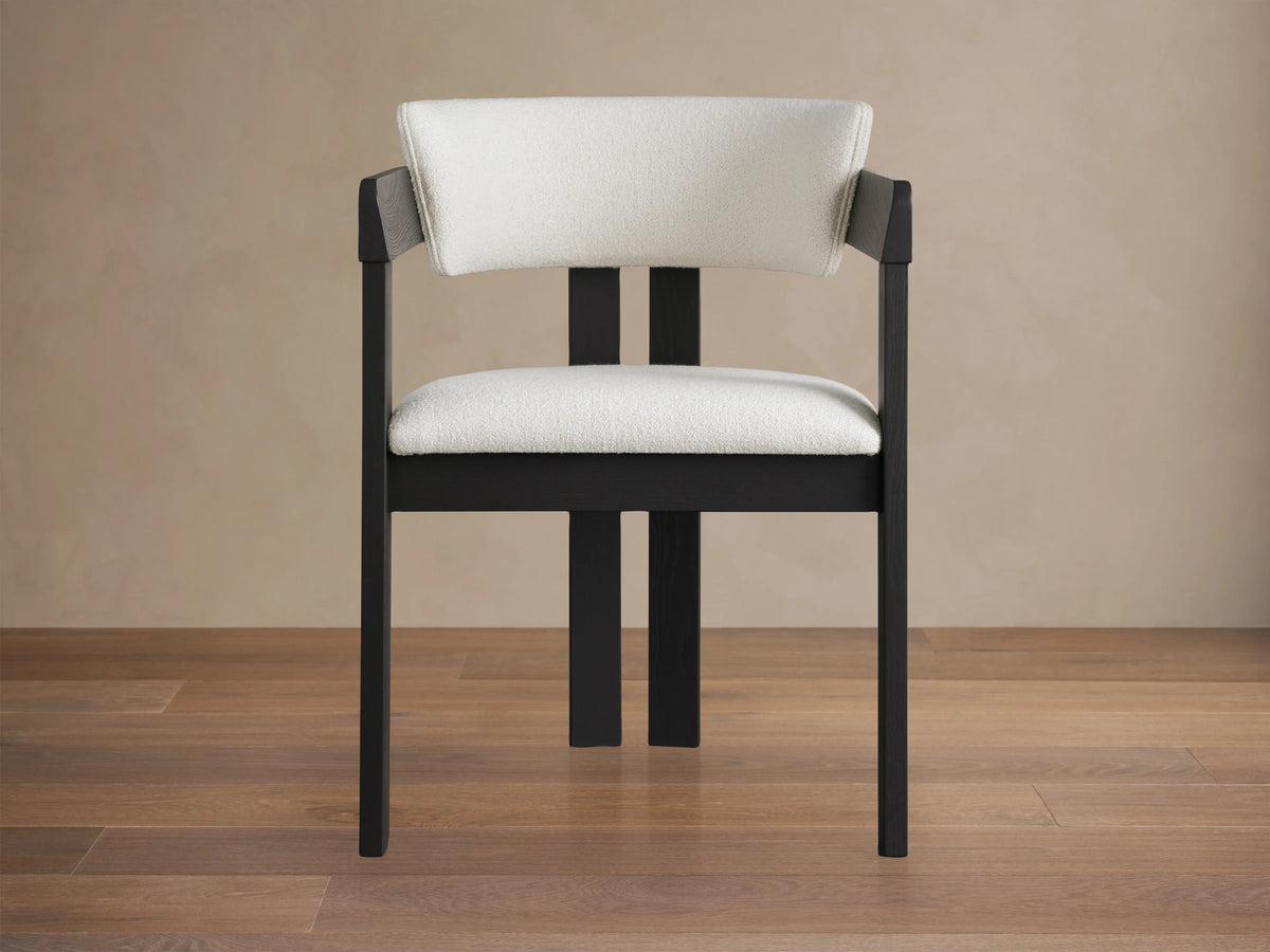 Rodin Dining Arm Chair made of dark ash wood with armrests, featuring a cushioned white seat and backrest on a wooden floor.