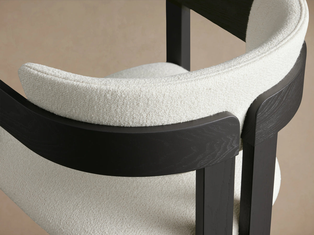 Rodin Dining Arm Chair, front view; features black ash wood frame and soft white upholstered seat and backrest on wooden floor.