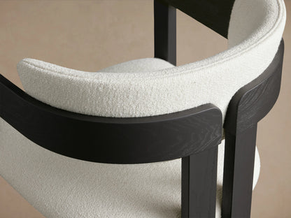 Rodin Dining Arm Chair, front view; features black ash wood frame and soft white upholstered seat and backrest on wooden floor.