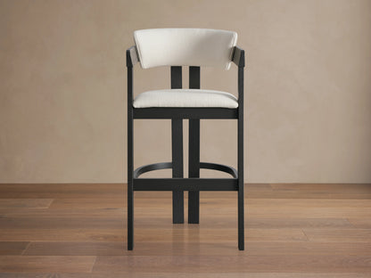 Rodin Stool with dark ash wood frame, cream cushion and backrest, soft fabric, on a wooden floor against a neutral wall.