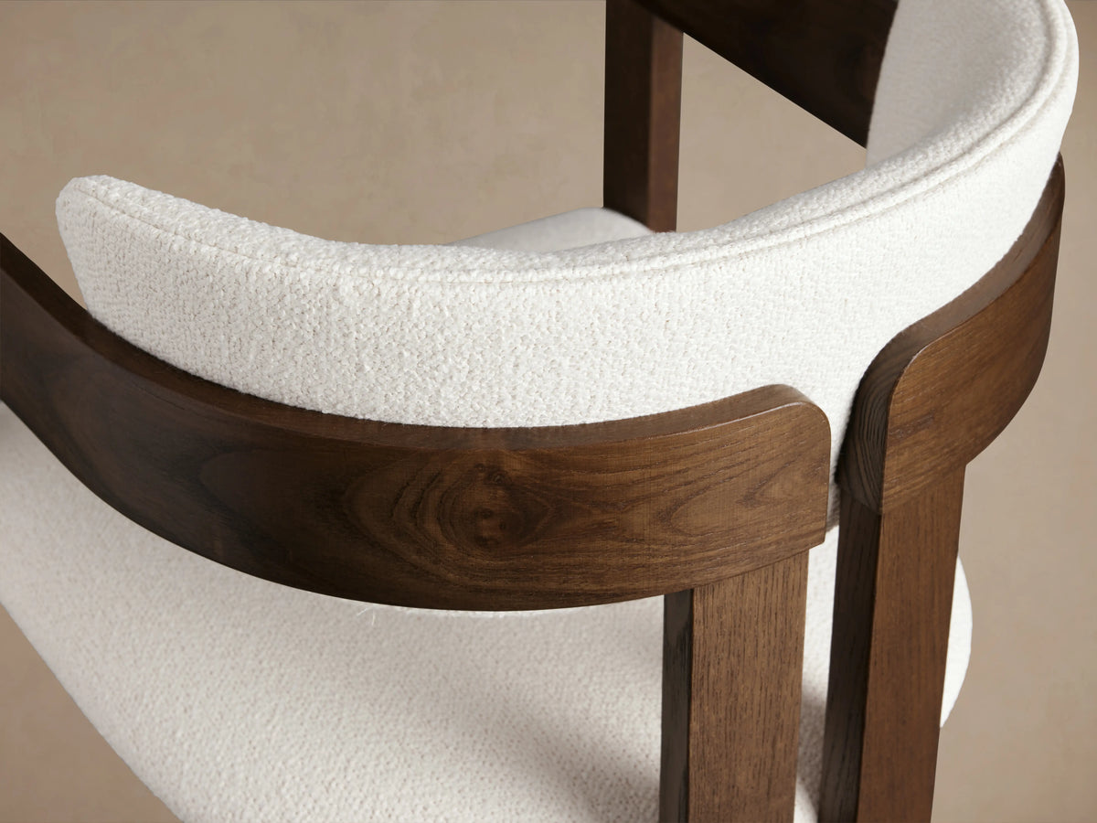 Rodin Dining Arm Chair in ash wood with hand-applied finishes, white cushioned seat and back, wooden arms and frame on wooden floor.