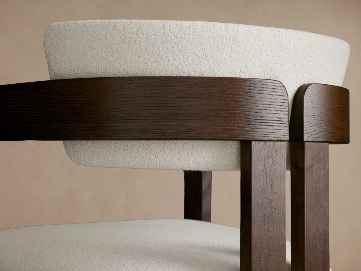 Rodin Stool featuring a dark ash wood frame with a round cream cushion. The stool has a curved back, showcasing its crafted detail.