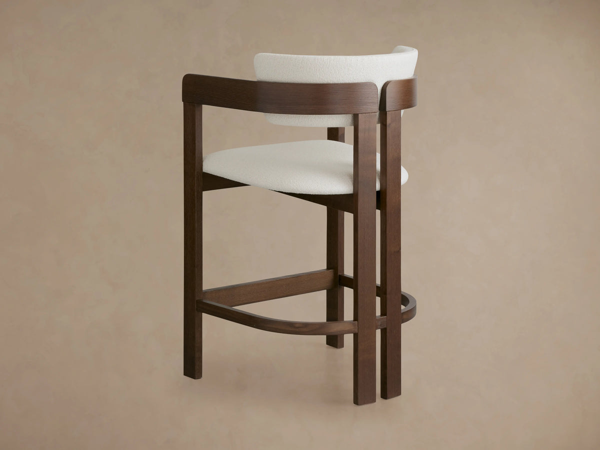 Rodin Stool with ash wood frame, dark brown finish, and white cushioned seat/backrest, set on wooden floor, light background.
