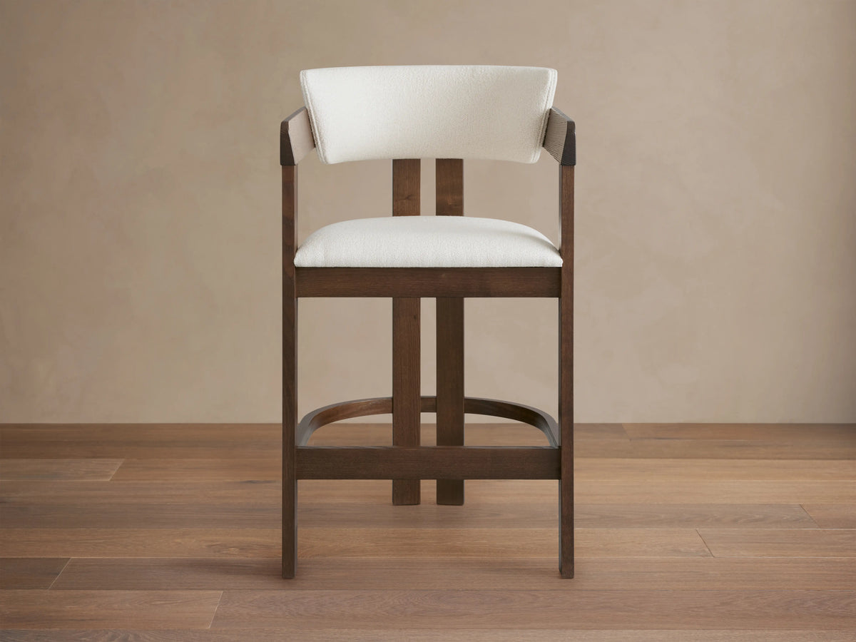 Rodin Stool featuring a curved ash wood frame with a dark finish and white cushioned seat and backrest, angled to the right.