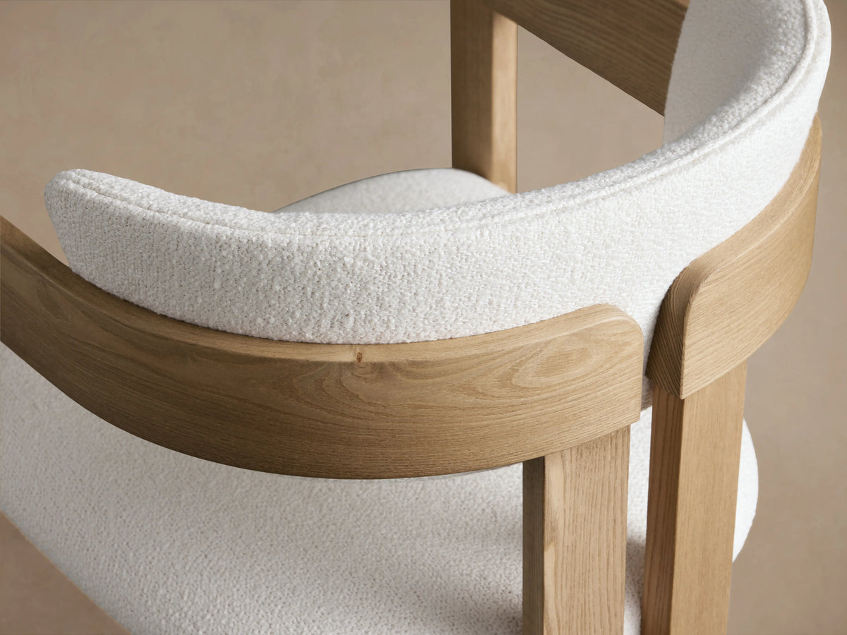 Rodin Dining Arm Chair in Natural; ash wood frame, white cushioned seat and backrest, on wooden floor, beige wall backdrop.