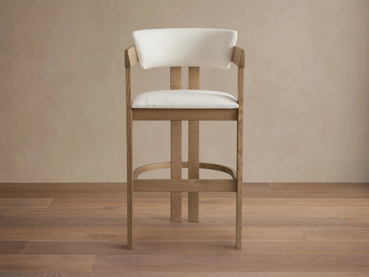 Rodin Barstool in Natural, made from ash wood with a warm finish, features white upholstered seat and back, and a rectangular footrest.