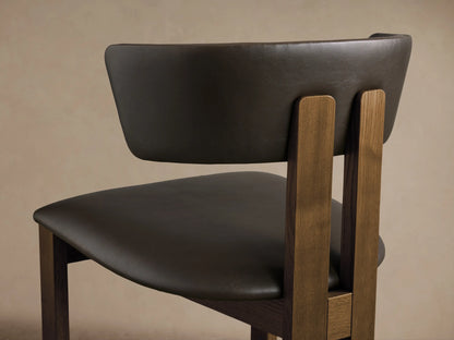 Rodin Faux Leather Dining Side Chair. Front view of dark brown faux leather seat/back and dark ash wood frame on wood floor.