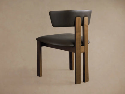 Rodin Faux Leather Dining Side Chair: angled close-up of dark brown faux leather seat and curved back, ash wood frame.