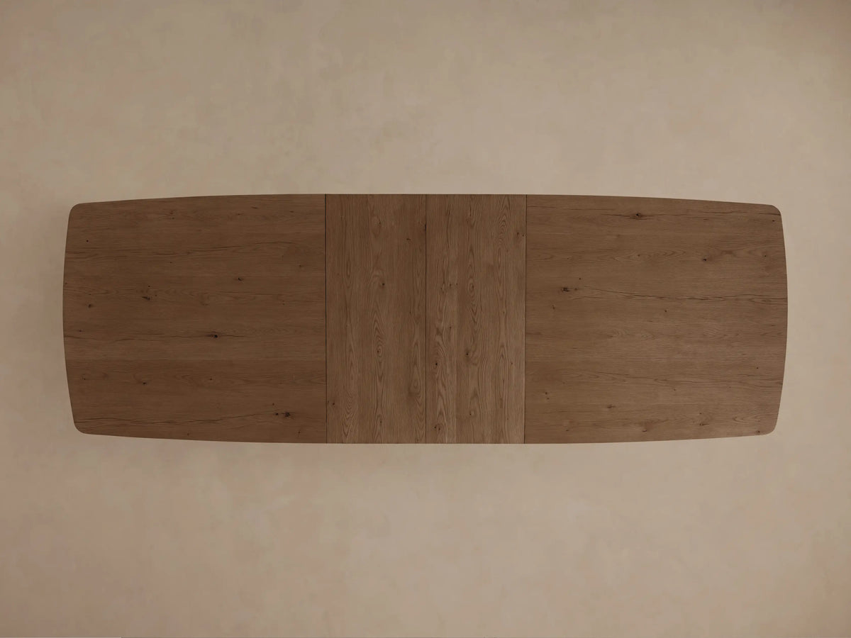 Front view of a dark brown wooden dining table with rounded corners, a central seam, and thick block legs connected by a stretcher.