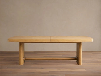 Full view of the light natural oak Redding Extension Dining Table, extended, in a bright dining room with cane chairs.