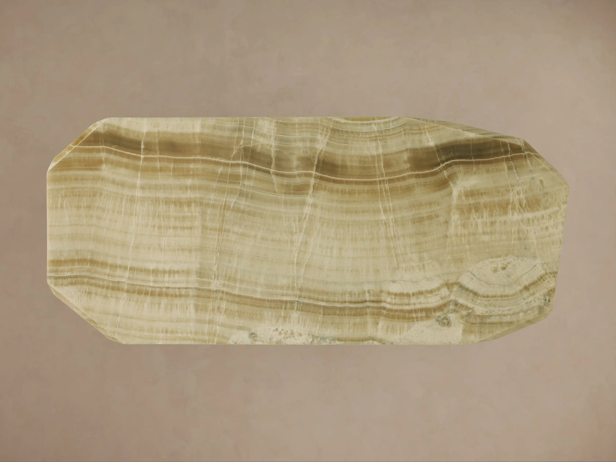 Angled close-up of Zyra Stone Dining Table. Solid green onyx top & geometric base with natural light green/brown veining.