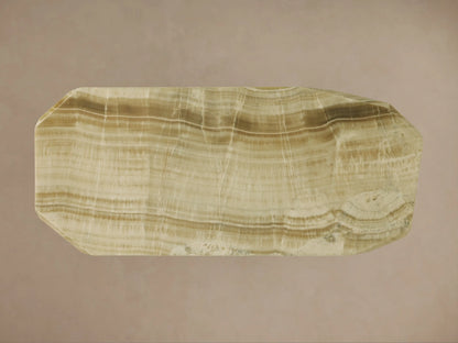 Angled close-up of Zyra Stone Dining Table. Solid green onyx top & geometric base with natural light green/brown veining.