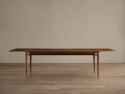 Ross Extension Dining Table made from walnut wood, featuring a long rectangular tabletop with patina brass leg caps and slender legs.