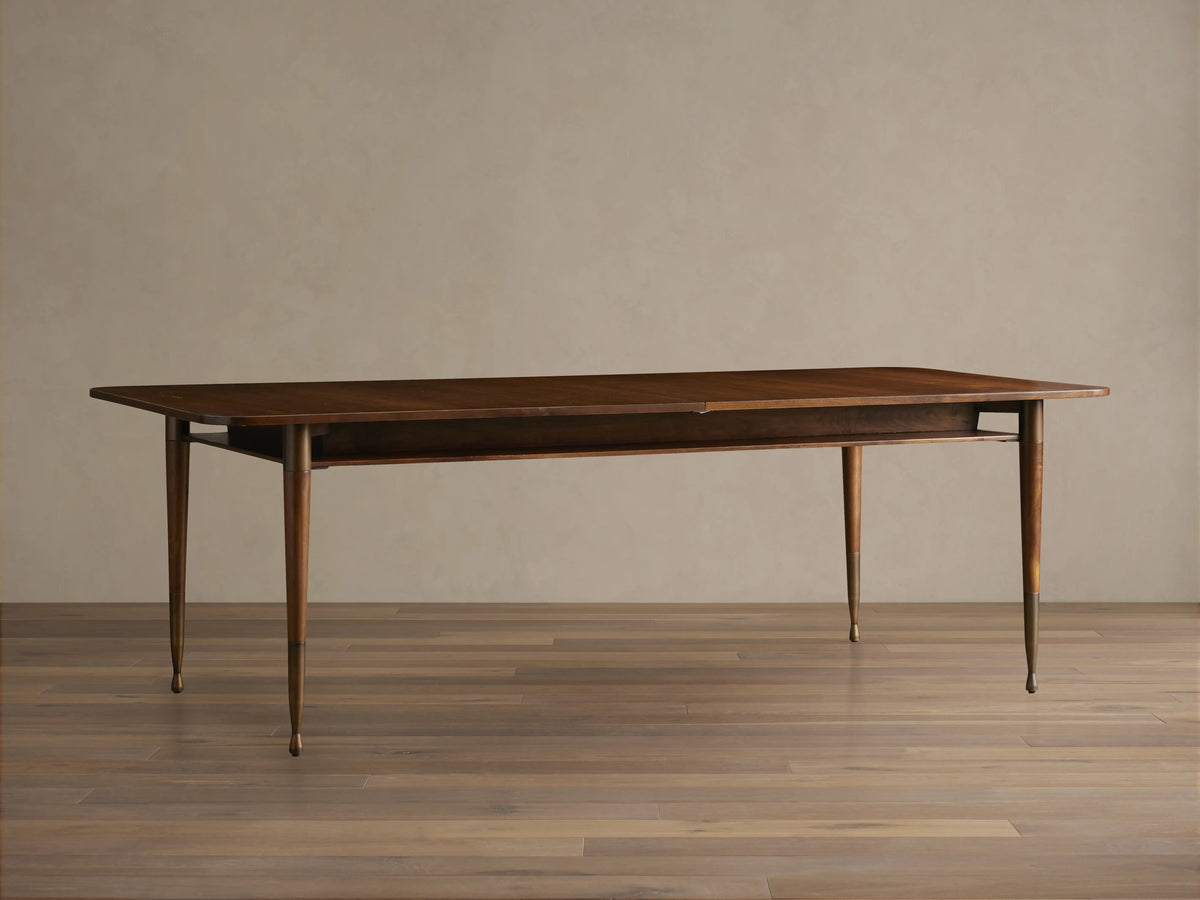 Ross Extension Dining Table in walnut wood with patina brass leg caps, featuring a mid-century design and floating shelf detail.