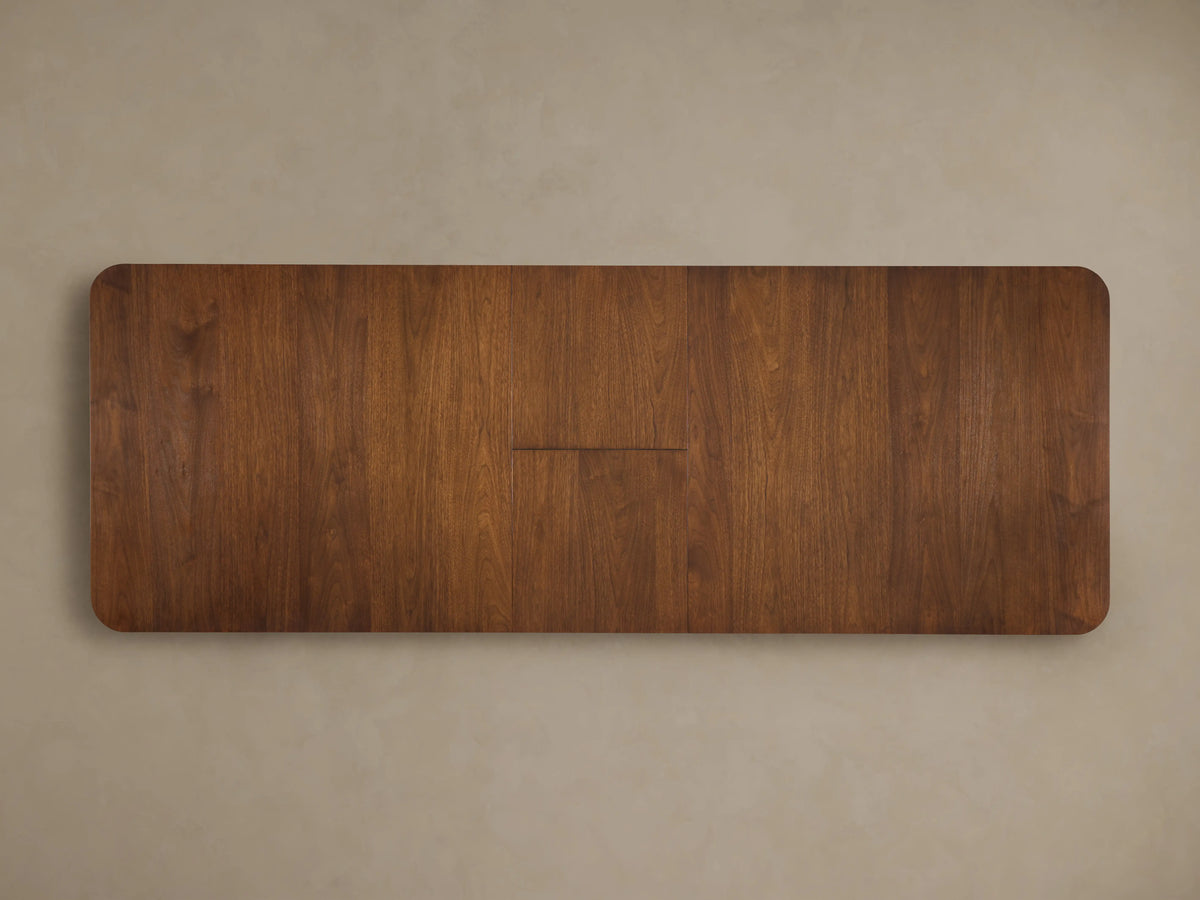 Ross Extension Dining Table with a self-storing leaf extended. Made of rich walnut wood with visible grain patterns and sleek, modern design.