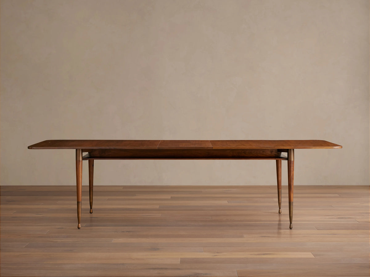 Ross Extension Dining Table made of solid walnut wood with brass leg caps, showcasing a mid-century design with a tabletop floating shelf.