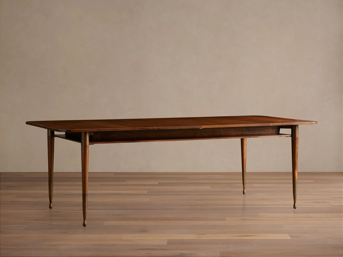 Ross Extension Dining Table in solid walnut wood with patina brass leg caps. Features a self-storing extension leaf and tapered legs.