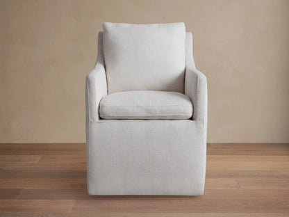 Samantha Dining Chair in light gray fabric with padded backrest and seat, featuring smooth lines and subtle curves on a wooden floor.