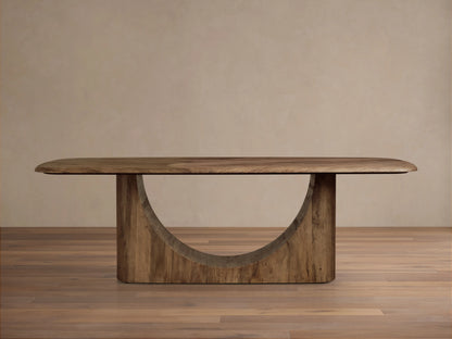 San Rafael Dining Table in primavera wood with a semi-matte finish, featuring a curved base and oval top, on hardwood floor.