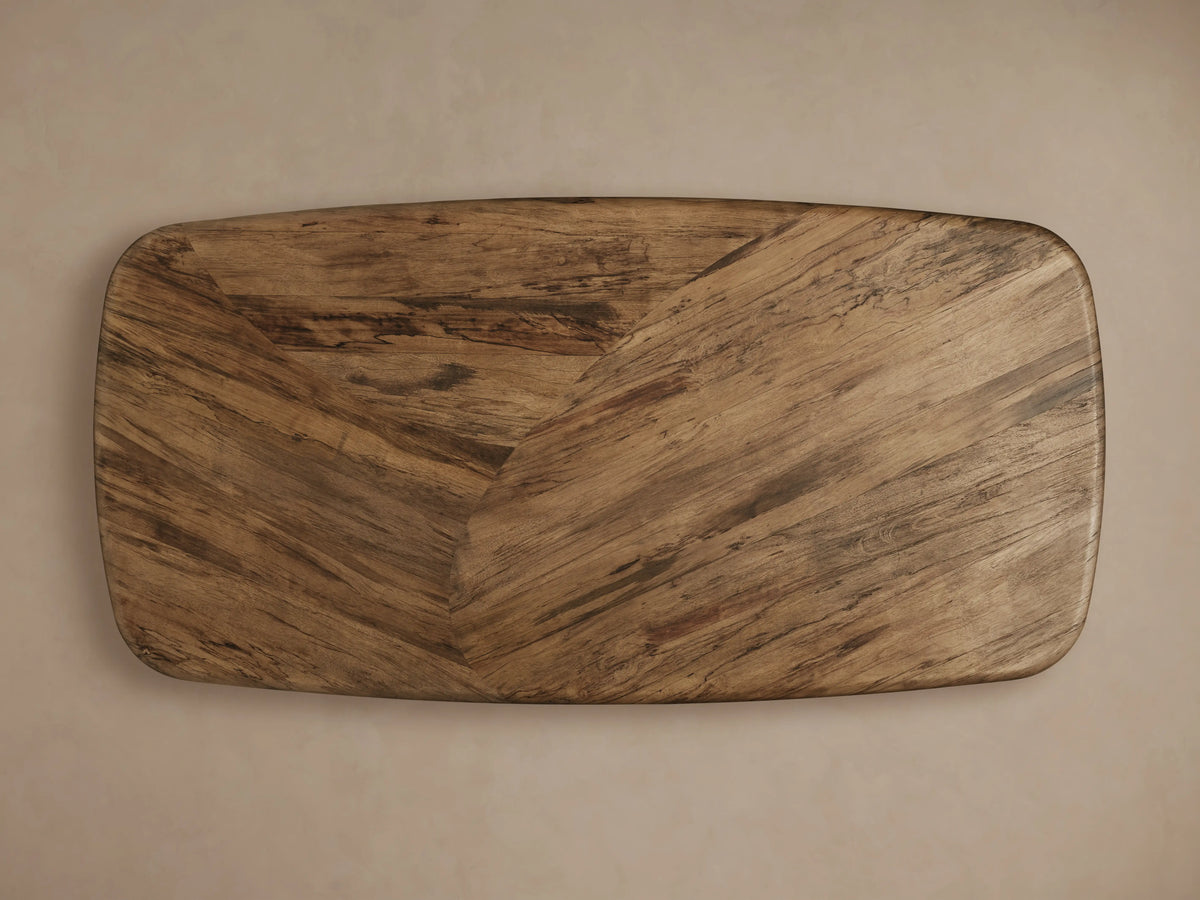 San Rafael Dining Table in primavera wood with a semi-matte finish, featuring a curved base and oval top, on hardwood floor.