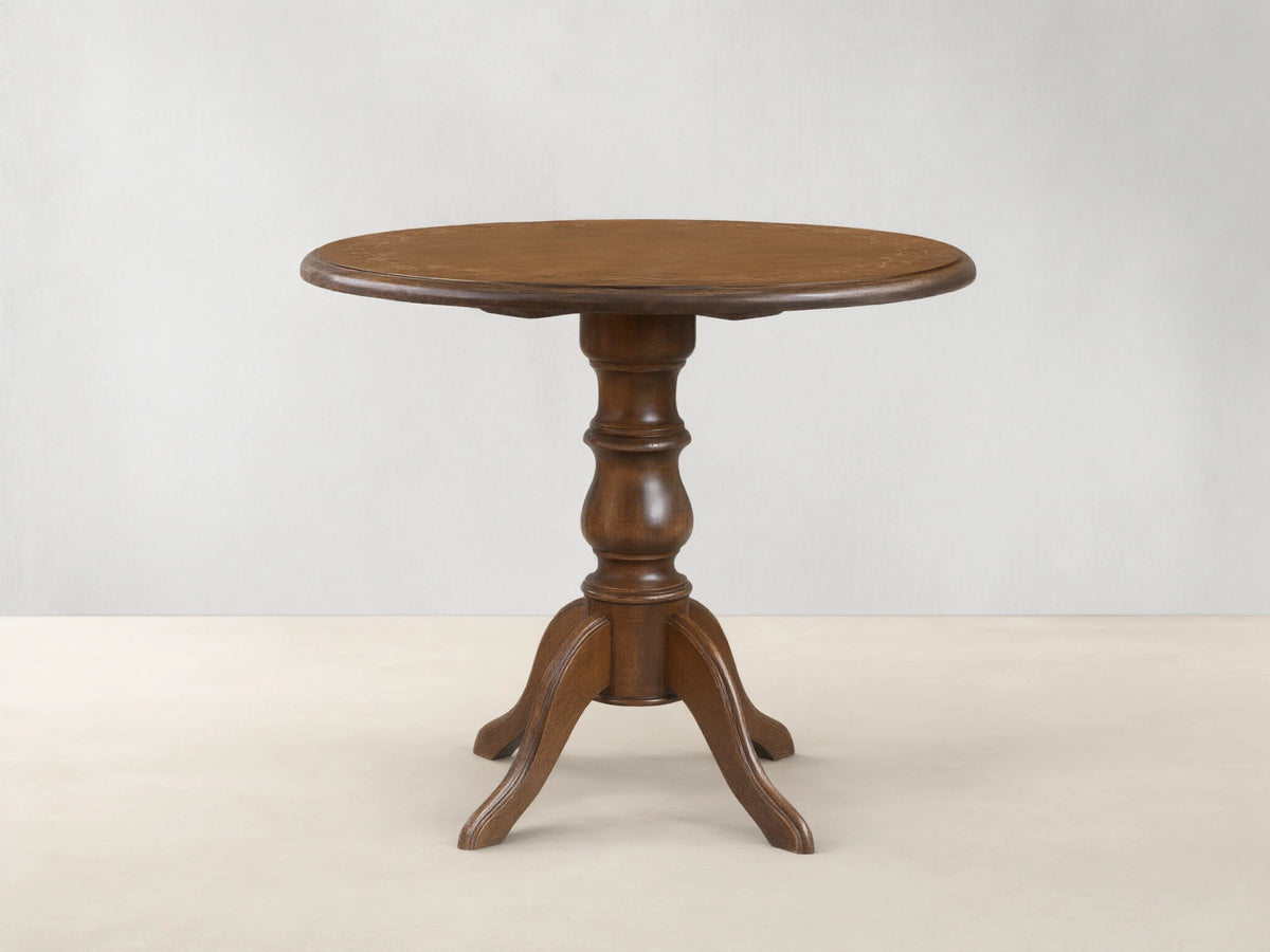 Front view of the brown Stefania Bistro Table with a round top, hand-painted botanical border, and a turned pedestal base.