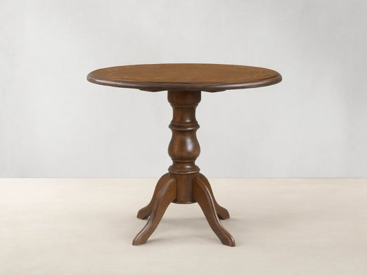 Front view of the brown Stefania Bistro Table with a round top, hand-painted botanical border, and a turned pedestal base.