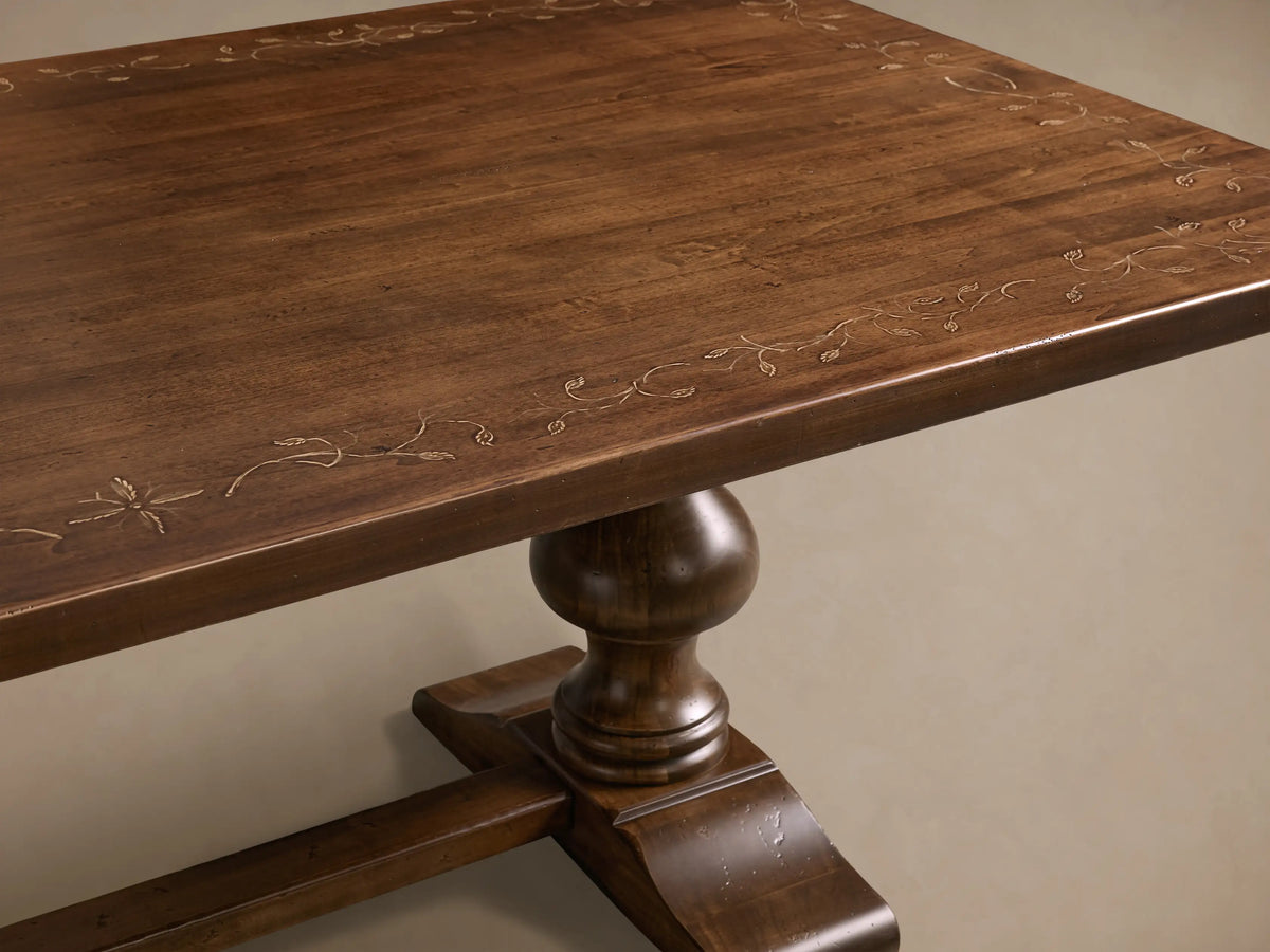 Front view of the dark brown Stefania Oval Extension Dining Table with hand-painted botanical motif and hand-turned pedestal legs.