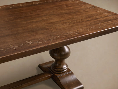 Front view of the dark brown Stefania Oval Extension Dining Table with hand-painted botanical motif and hand-turned pedestal legs.