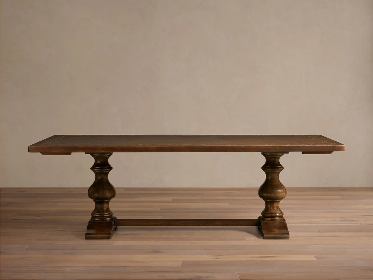 Front view of the dark wood Stefania Oval Extension Dining Table with two hand-turned pedestal legs and an oval top.
