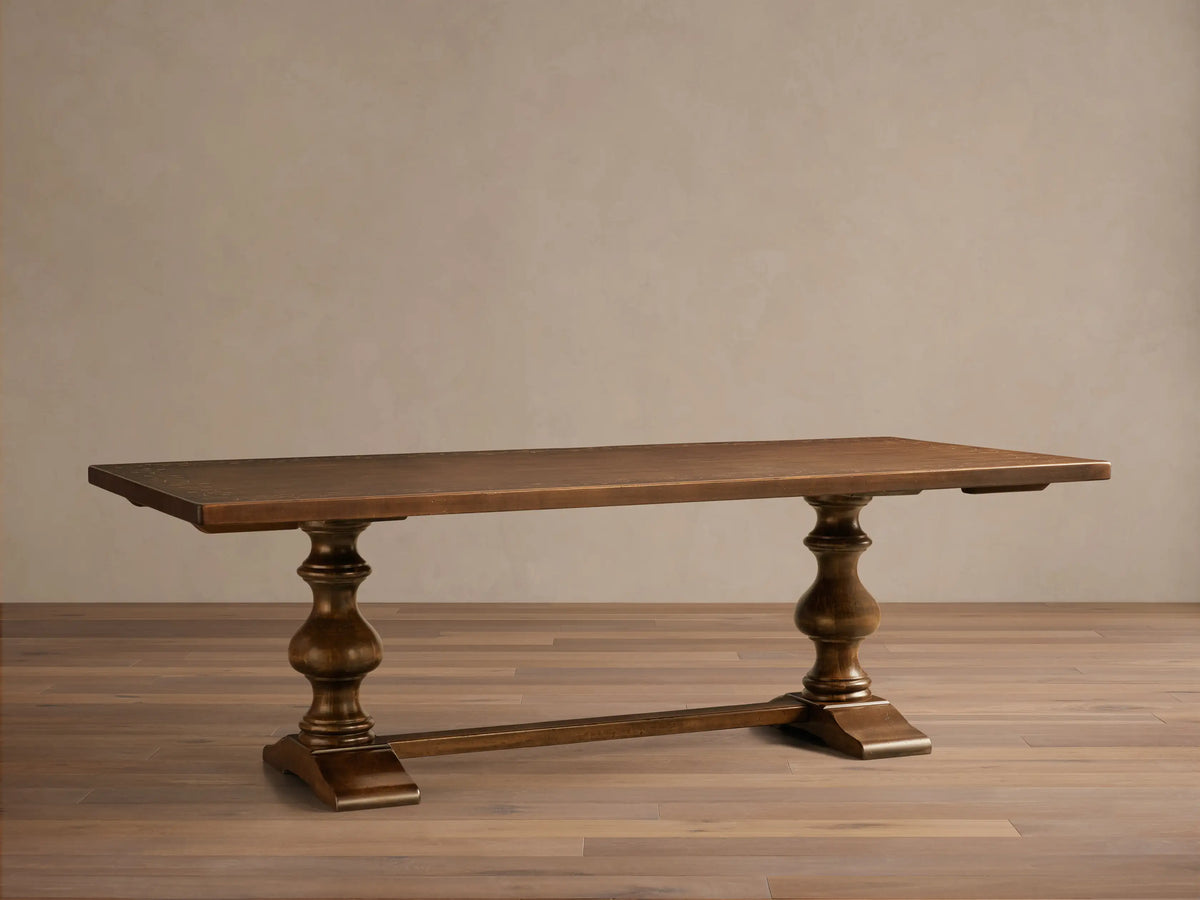 Front view of the dark brown Stefania Oval Extension Dining Table, featuring hand-turned pedestal legs and a subtle botanical tabletop.