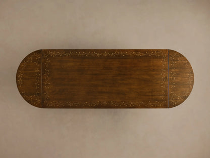 Close-up angled view of the dark brown Stefania Oval Extension Dining Table, showing the hand-painted leafy botanical motif on the tabletop and part of the hand-turned pedestal leg.
