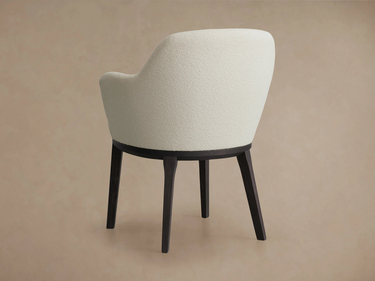 Simone Dining Arm Chair with cream upholstered backrest, dark wooden base, and four tapered legs, viewed from the back.