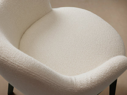 Simone Dining Arm Chair with cream upholstered seat and backrest, dark ash wood frame, on a wood floor, against a beige wall.