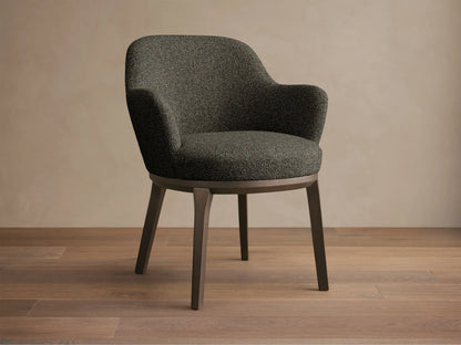 Front view of the dark gray tweed Simone Dining Arm Chair with dark wood legs and a rounded back.