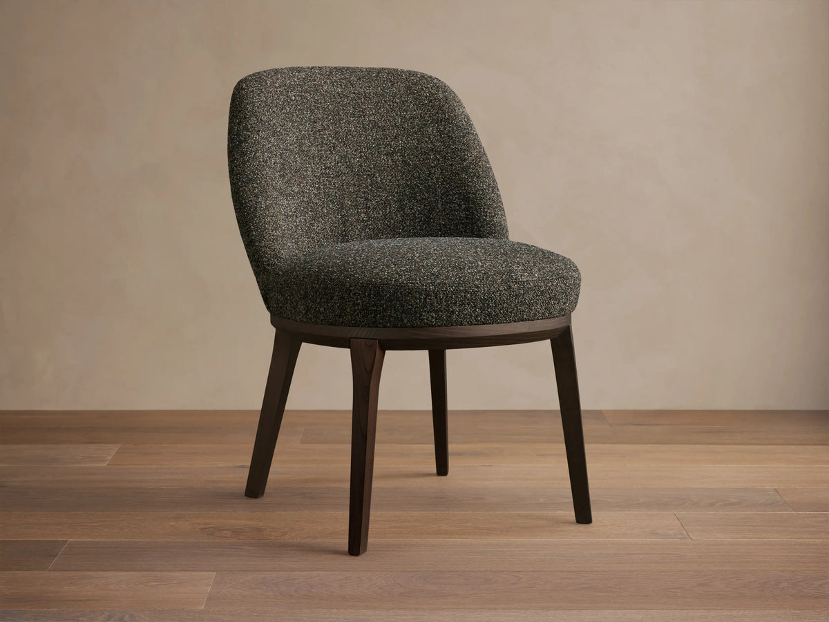 Front view of a dark speckled upholstered Simone Dining Side Chair with dark wood legs and a curved back.