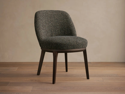 Front view of a dark speckled upholstered Simone Dining Side Chair with dark wood legs and a curved back.