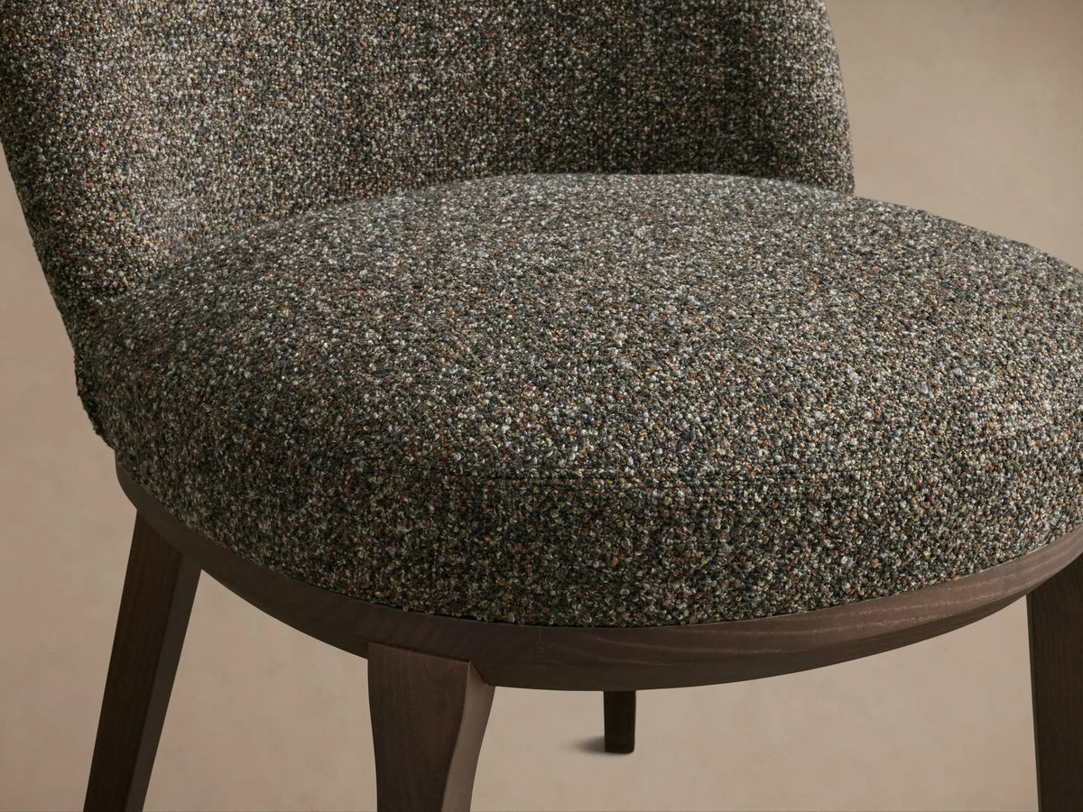 Close-up of the textured brown and grey upholstery on the Simone Dining Side Chair's seat and lower back, with dark wood base.