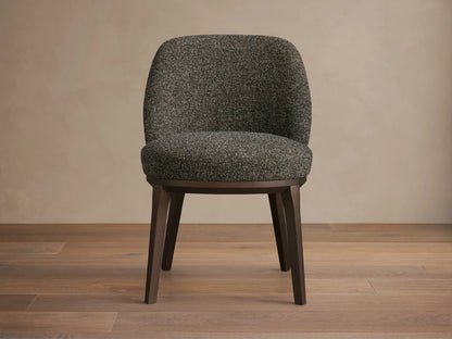 Front view of a dark speckled upholstered Simone Dining Side Chair with dark wood legs and a curved back.